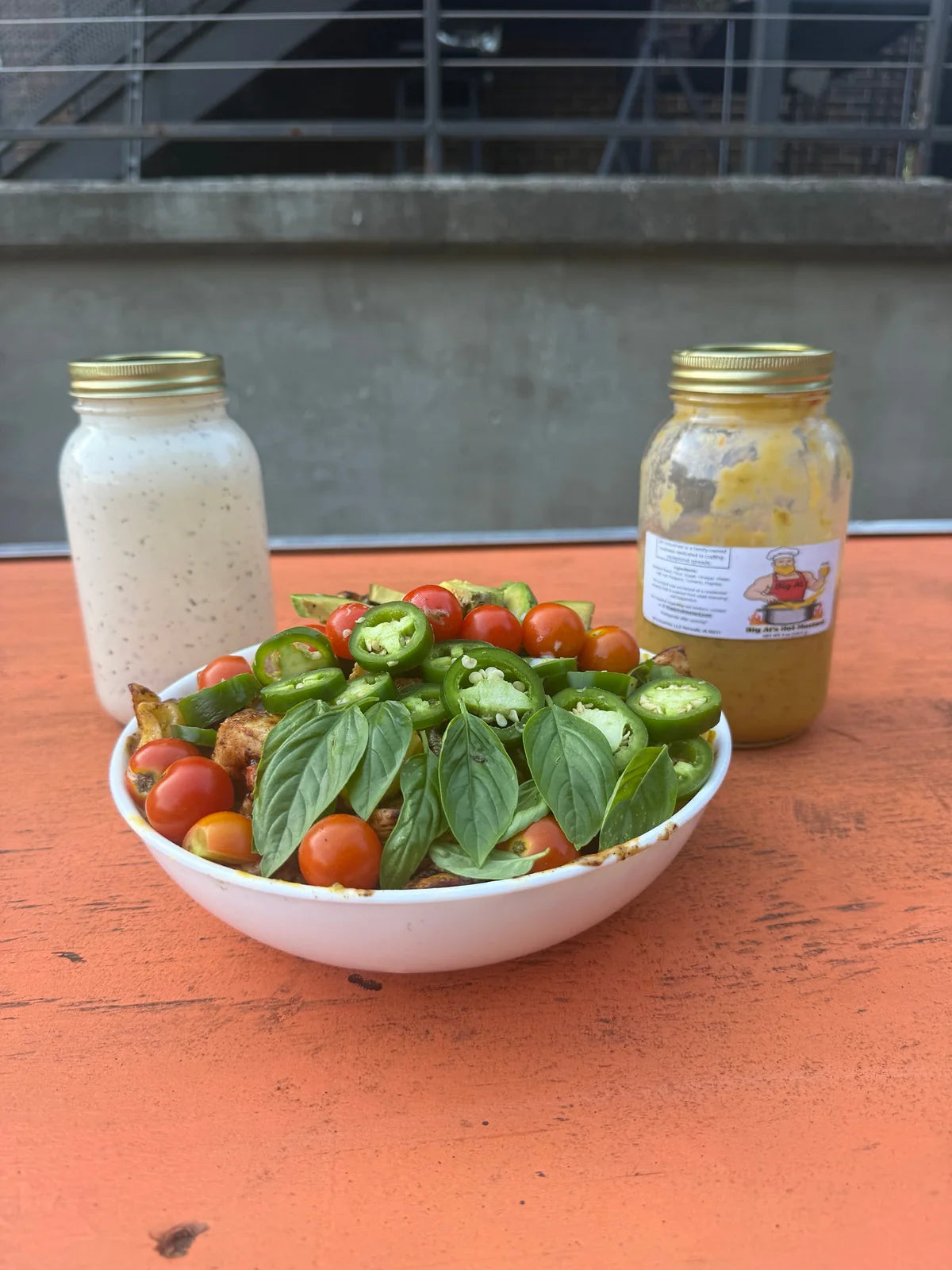A Southwest chicken tortellini bowl topped with cherry tomatoes, jalapeños, basil and avocado, next to a jar of Big Al's Hot Mustard
